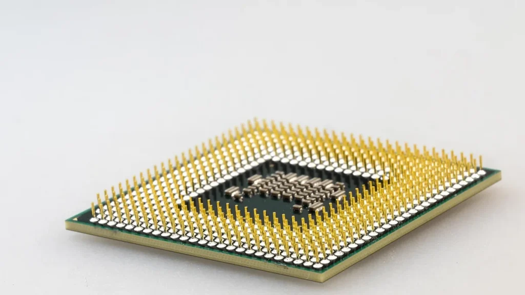 A close-up of a computer processor CPU with gold pins on a plain white background.