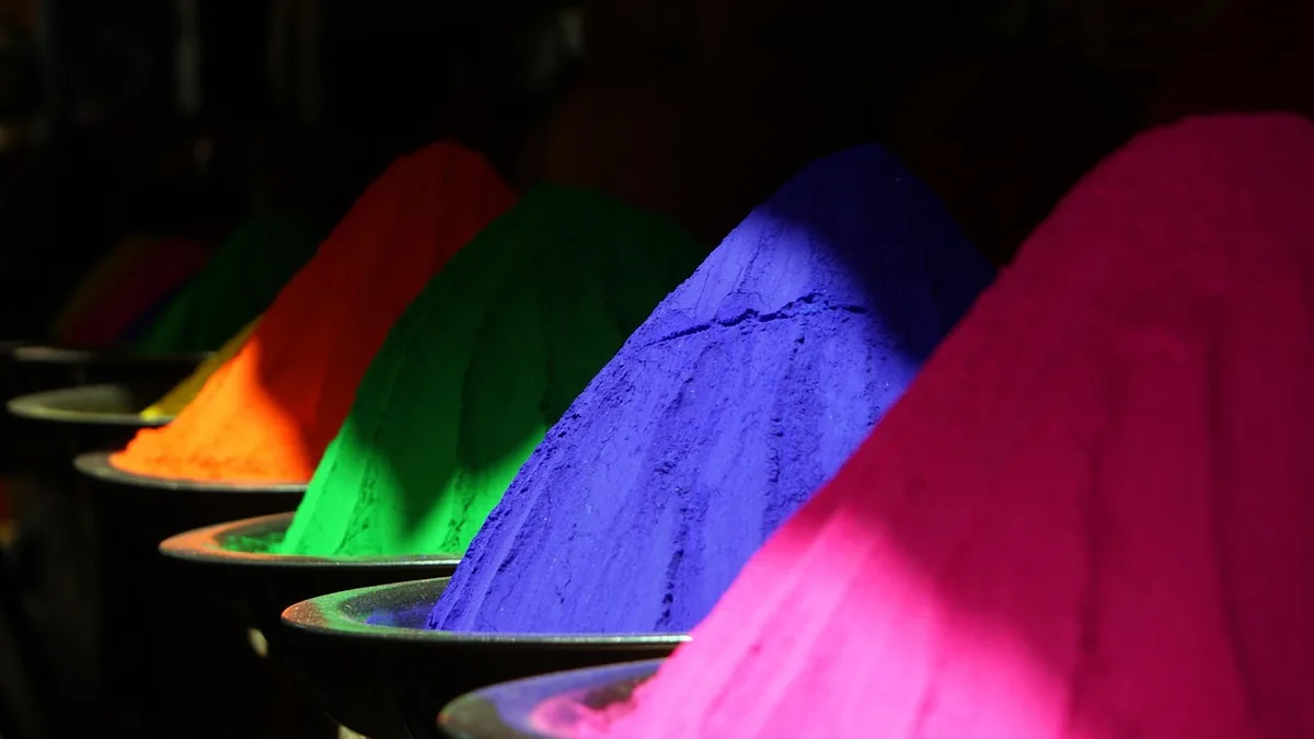 Vibrant piles of colorful powder in orange, green, blue, and pink arranged in bowls.