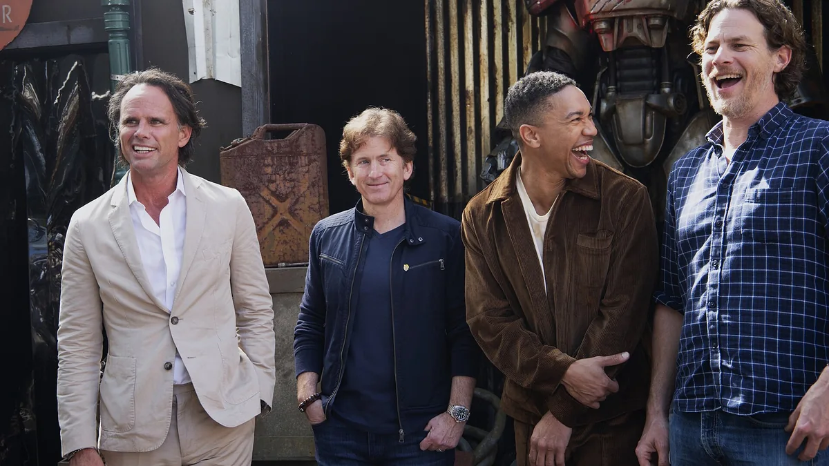 Four men, including Todd Howard and Walton Goggins, smiling and laughing together outdoors.