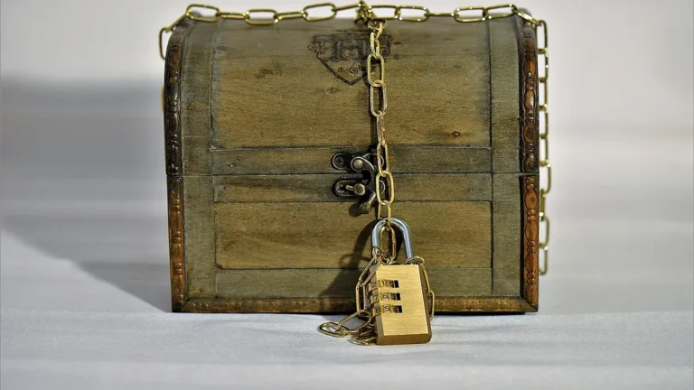 Wooden treasure chest wrapped in a gold chain and locked with a brass combination padlock.