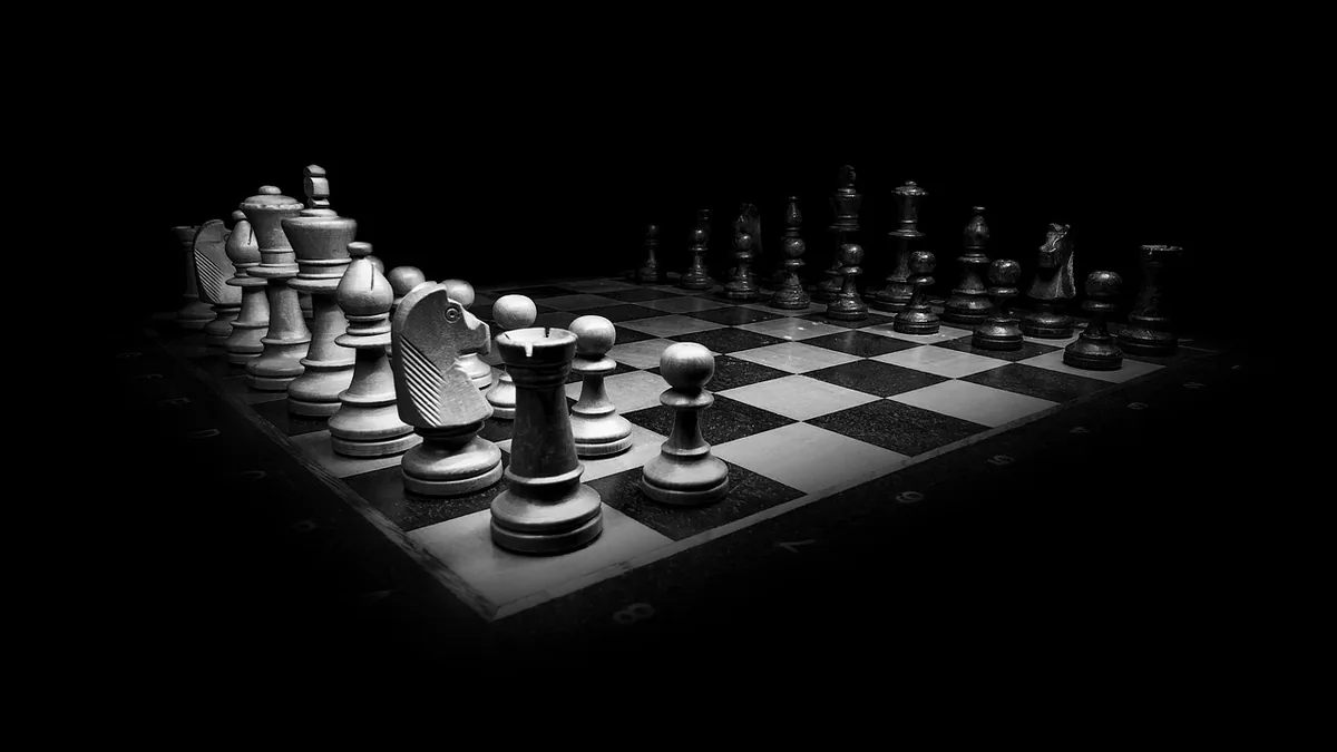 Dramatic black and white chess board set for a strategic game under dark lighting.