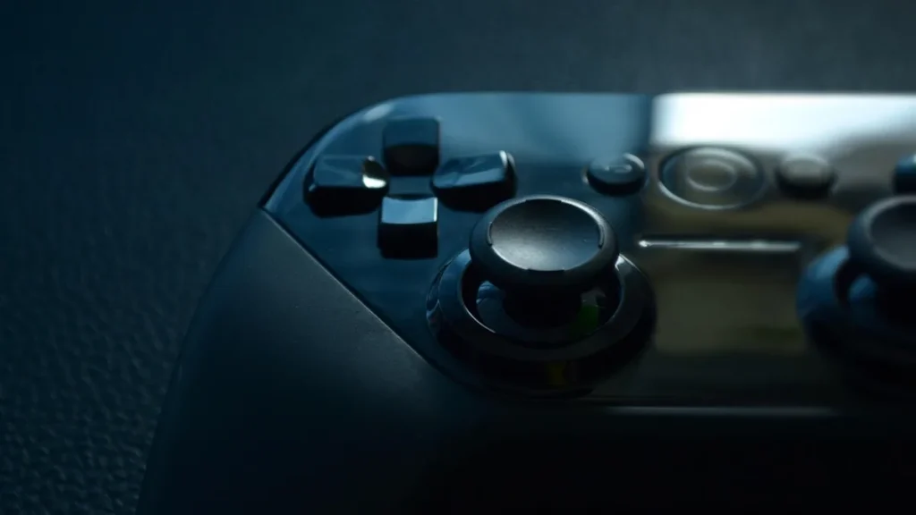 Close-up of a glossy black gaming controller showing the D-pad and analog stick under dark blue lighting.