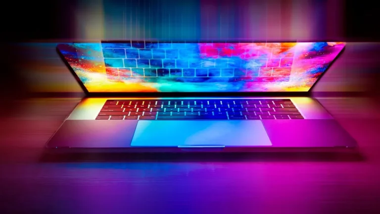 A vibrant laptop glowing with intense pink, blue, and yellow colorful lights, showing a keyboard reflection on screen.