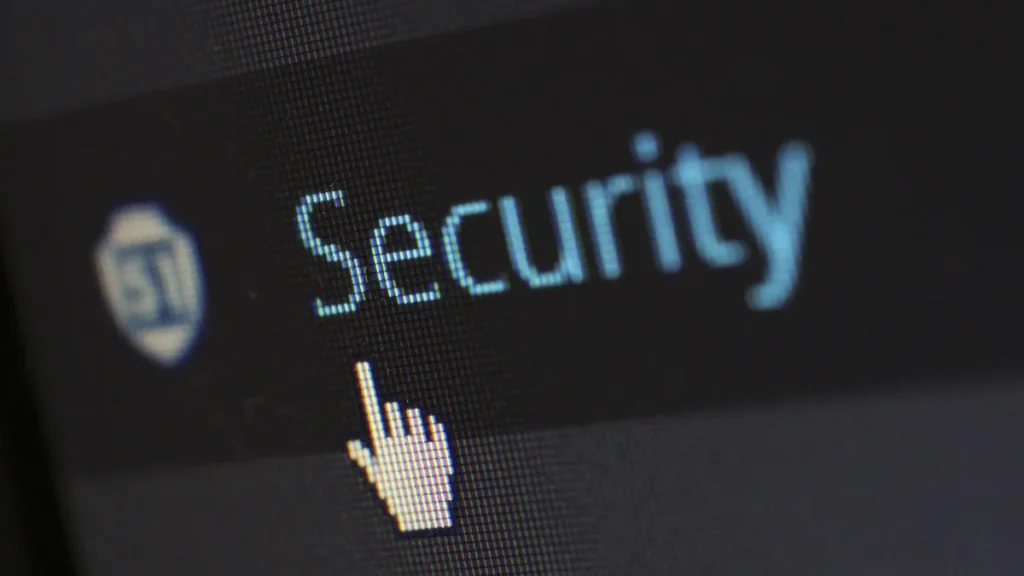 Pixelated cursor pointing at the pixelated word 'Security' next to a shield logo on a dark screen.