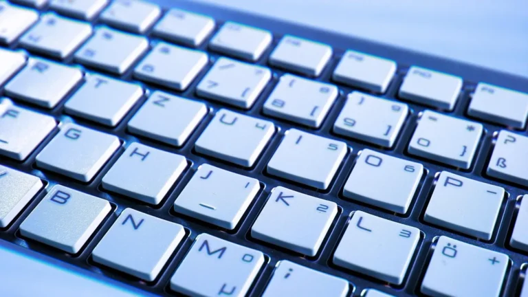A close-up, angled shot of a white chiclet keyboard glowing under cool blue light.