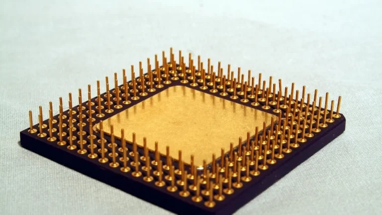 A gold-pin computer processor chip on a light gray background.