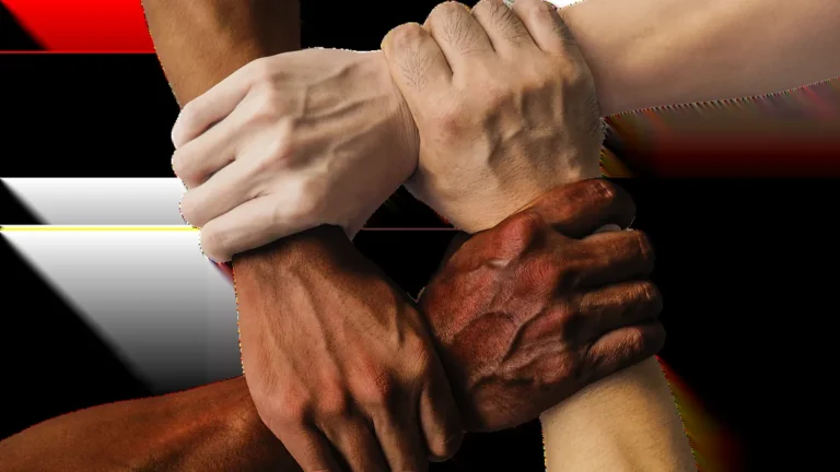 Diverse hands clasped in a circle, symbolizing unity, teamwork, and community cooperation.