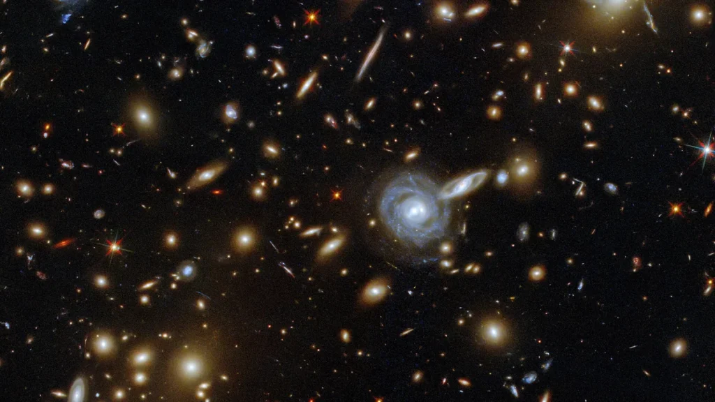 Deep space field showing numerous colorful spiral and elliptical galaxies scattered across the dark universe.