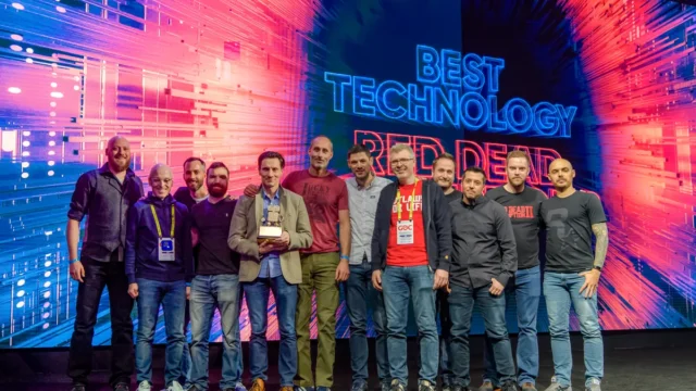 Group of developers on stage holding a 'Best Technology' award under a vibrant red and blue screen.
