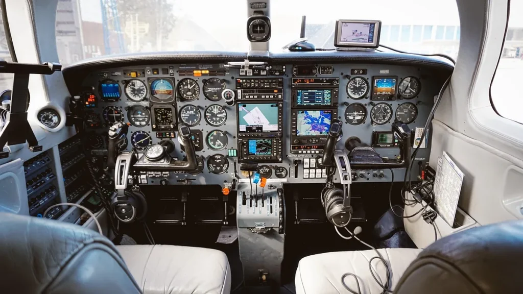 Interior view of a modern airplane cockpit showing dual control yokes, instrument panels, and navigation screens.