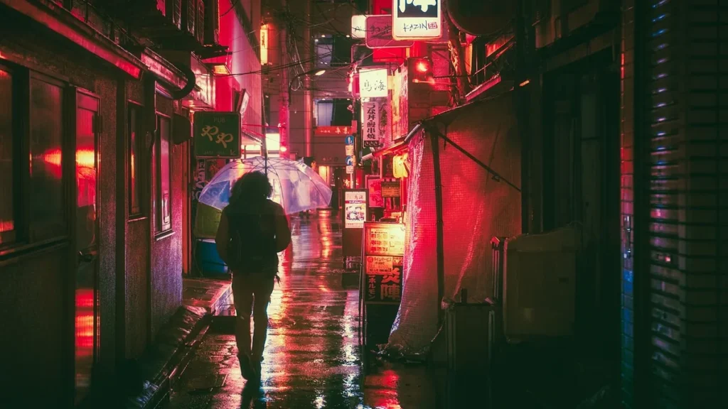 Person walking with a clear umbrella in a wet, neon-red glowing Japanese alley at night.