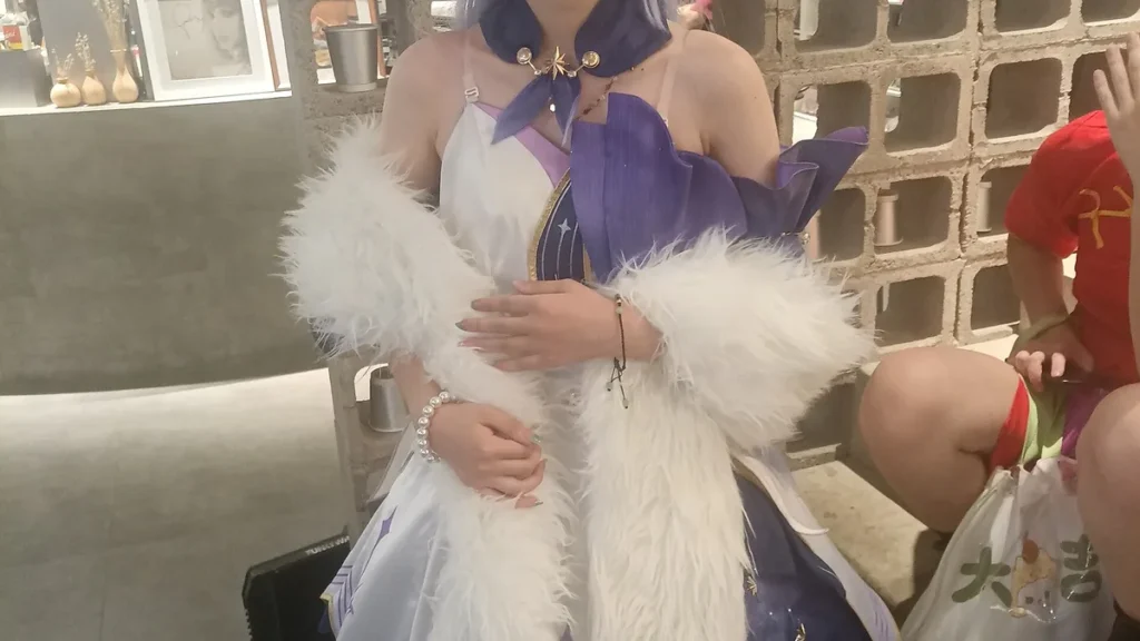 Cosplayer in a purple and white dress with a star clasp and white furry shawl, posing with hands clasped.