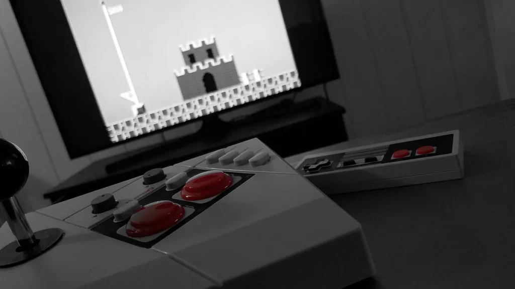 Retro arcade stick and NES-style controller with red buttons, showing a classic Mario level on a TV screen in black and