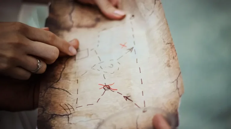 Hands holding and pointing at a parchment map with hand-drawn routes and red crosses.
