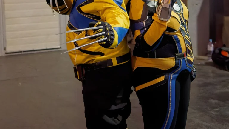 Two cosplayers in yellow and blue Wolverine suits pose with claws out.