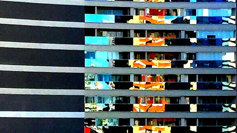 Abstract close-up of a modern building facade with colorful glass reflections and horizontal stripes.