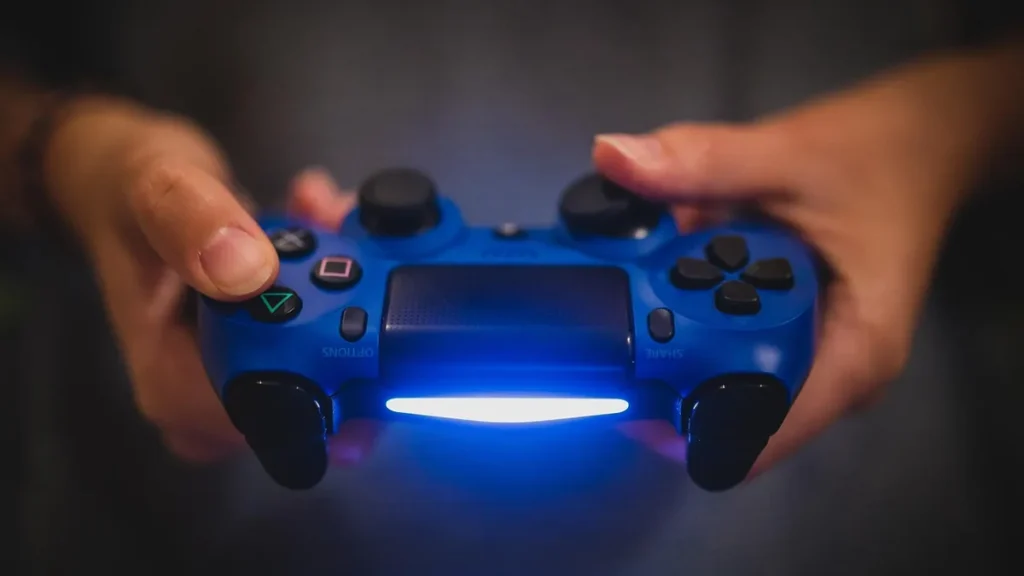 A close-up of hands holding a glowing blue PlayStation controller.