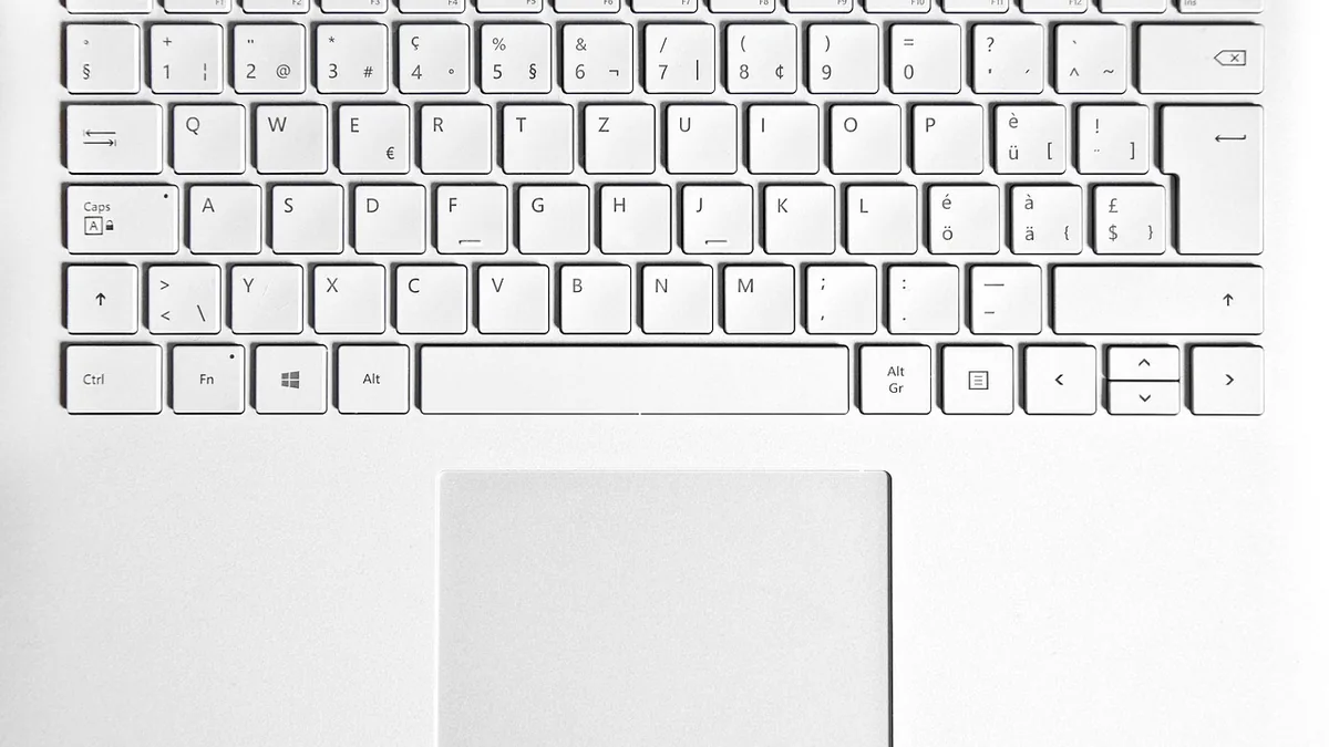 Top-down view of a clean white laptop keyboard with a large touchpad, showing a minimalist design.