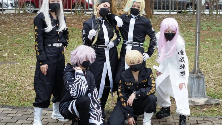 Group of cosplayers dressed as Tokyo Revengers characters, including Mikey and Draken, pose in black and white gang uniforms.