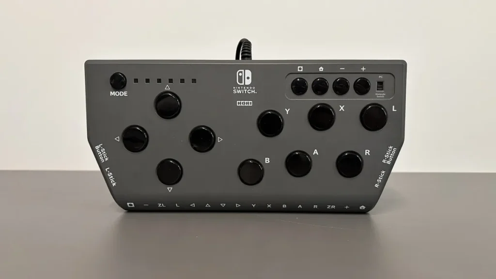 Grey Hori Nintendo Switch controller with multiple black buttons displayed on a grey surface.