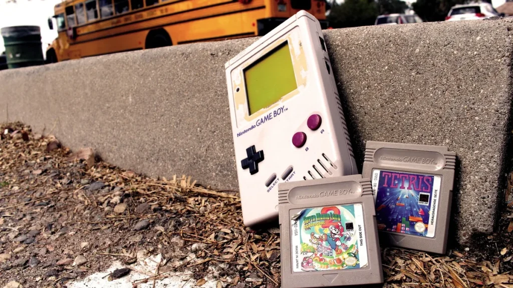 Vintage grey Game Boy console with Tetris and Super Mario Land cartridges on concrete.