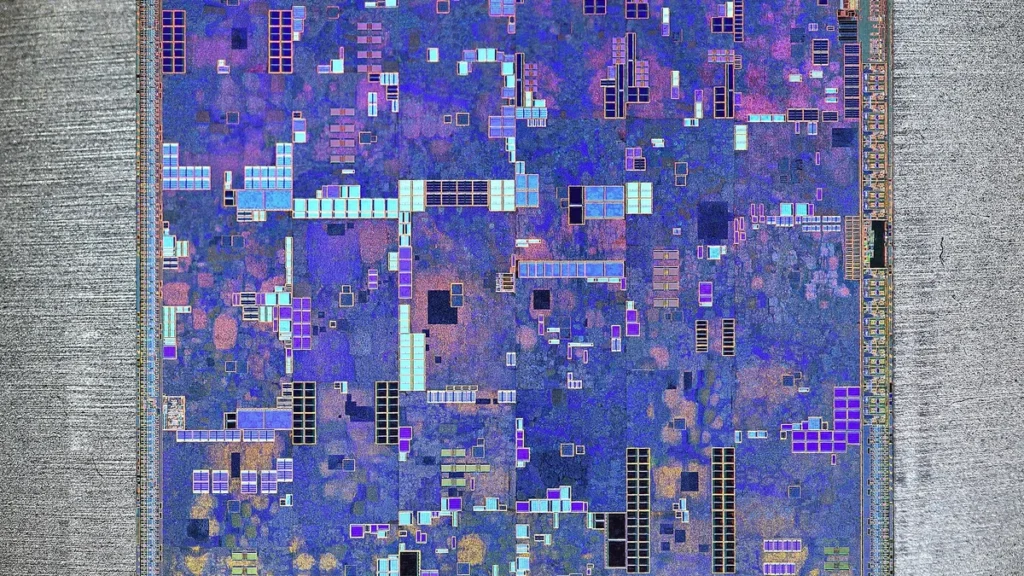 Colorful close-up of a silicon processor die with intricate blue, purple, and gold microcircuitry patterns.