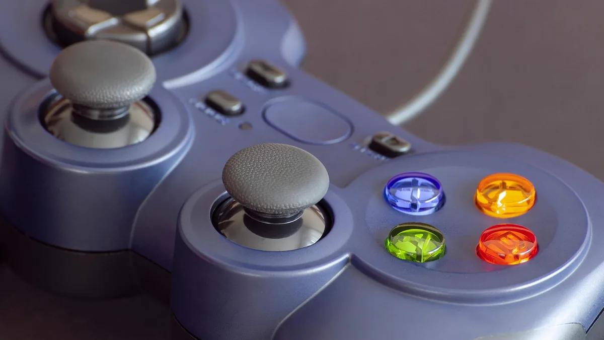 Purple game controller with colorful translucent buttons and textured grey analog sticks.