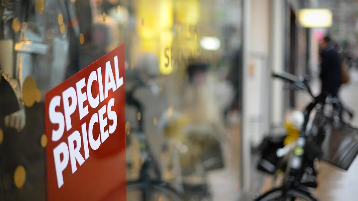 A red sign with white text reading 'SPECIAL PRICES' on a glass window, with a blurry street background.
