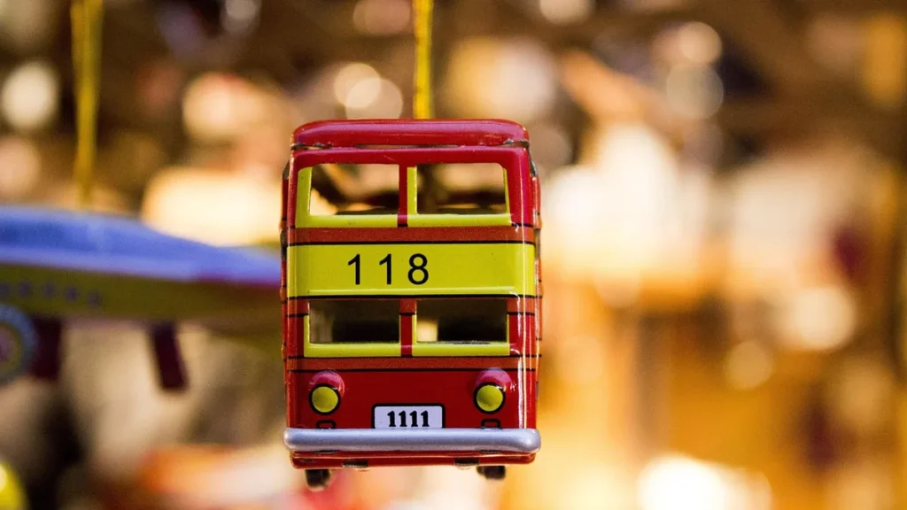 Red toy double-decker bus ornament with route number 118 hanging against a bokeh background.