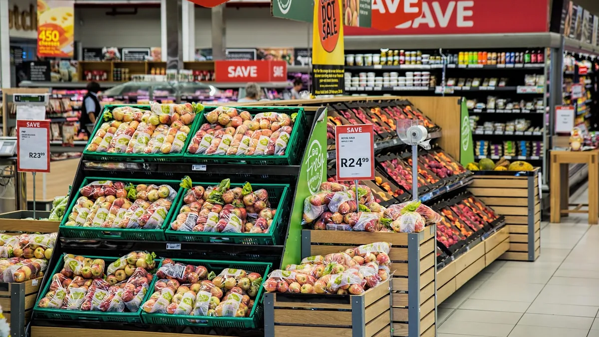 Bagged apples on supermarket shelves with prominent red price tags showing promotional retail prices.