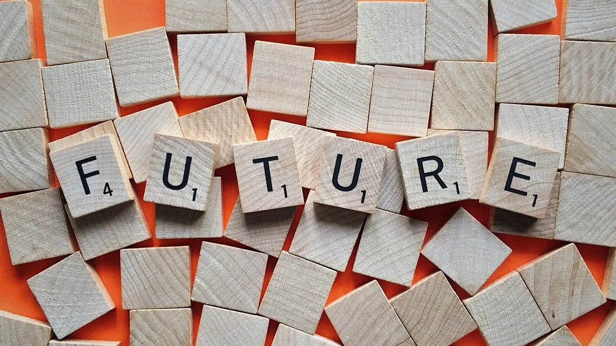 Wooden letter tiles spelling FUTURE surrounded by blank tiles on an orange background.