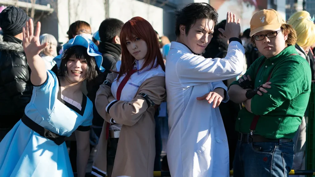 Cosplayers dressed as Steins;Gate characters Okabe, Kurisu, Mayuri, and Daru pose together outdoors.
