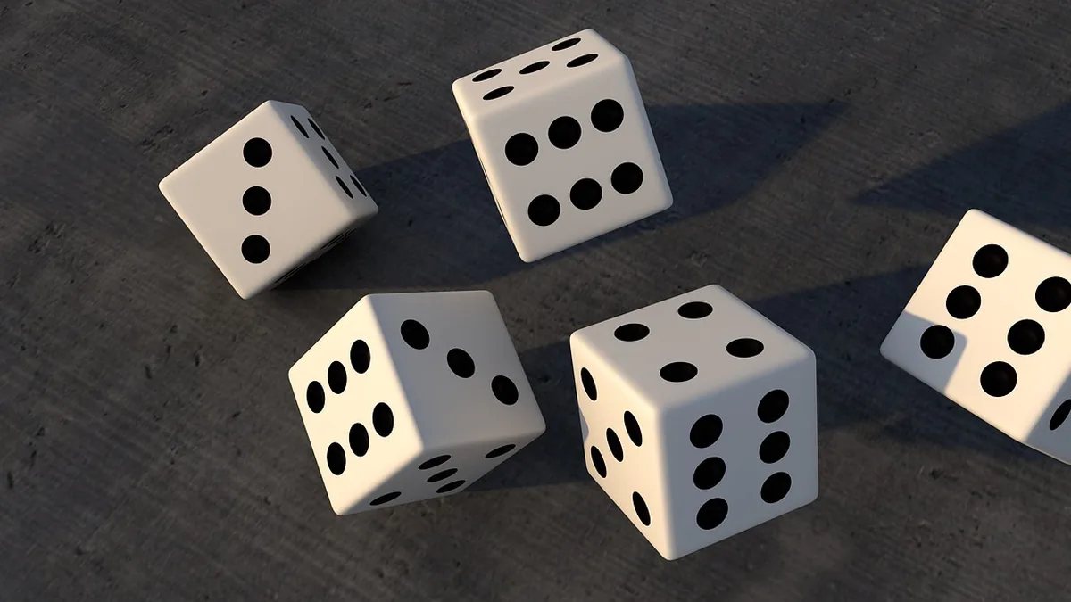 Five white dice showing different numbers scattered on a dark grey surface.
