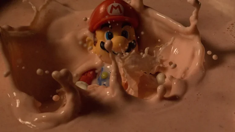 Toy Mario figure splashing into a creamy pink liquid, creating a dynamic crown-like splash around him.