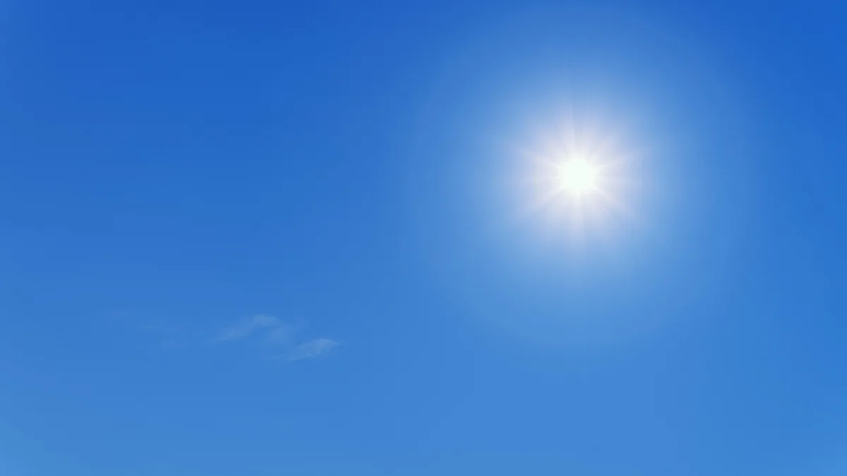 A bright sun shining brilliantly in a clear blue sky.