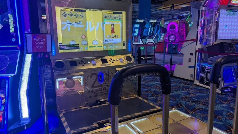 Arcade gaming machines with neon lights and classic game interfaces in an indoor setting