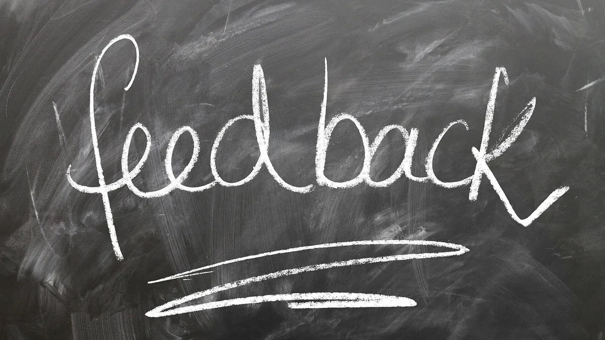 The word 'feedback' written in cursive white chalk on a dark, smudged blackboard with underlines.