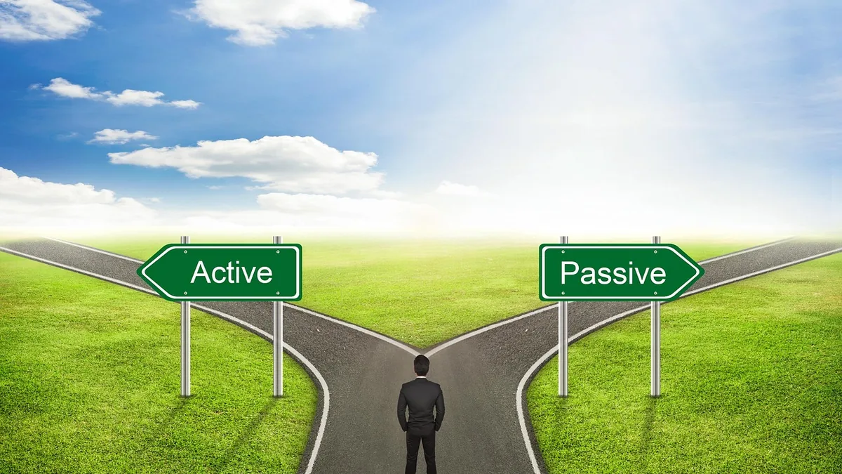 A man in a suit stands at a fork in the road, looking at signs pointing to 'Active' and 'Passive' paths.