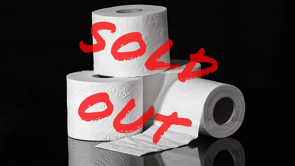White rolls of patterned toilet paper stacked on a black reflective surface, overlaid with bold red text reading 'SOLD OUT'.
