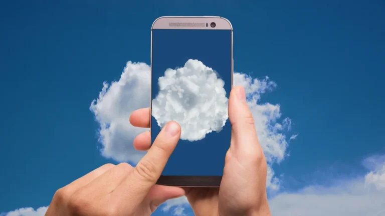 Hands holding a smartphone displaying a cloud against a blue sky, symbolizing cloud gaming.
