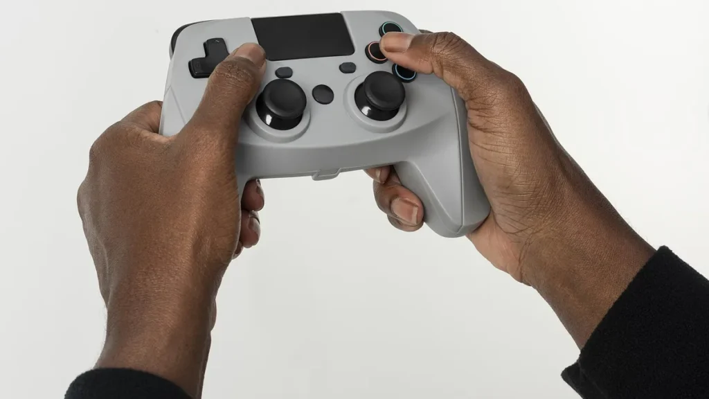 Close-up of a person's hands holding a grey video game controller against a clean white background.