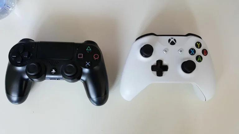 Black PS4 and white Xbox controllers side-by-side on a clean white tabletop.
