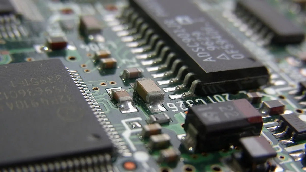Close-up macro shot of a green circuit board with microchips and small electronic components.